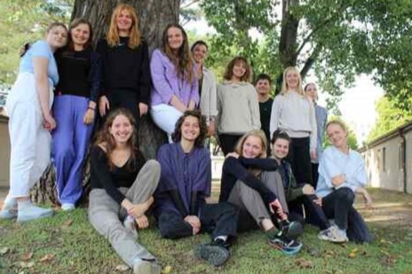 Gruppe eines Summer Study Camps vor einem Baum, im Hintergrund Baracken